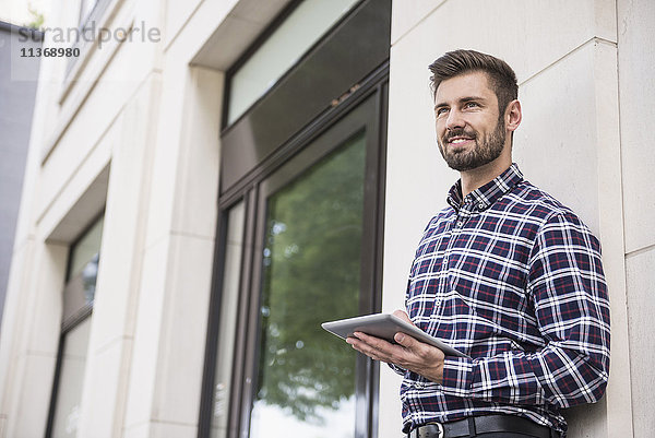 Junger Mann arbeitet an einem digitalen Tablet an der Wand