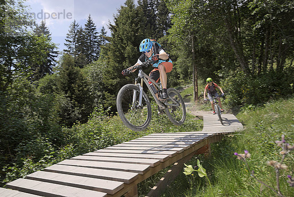 Zwei Mountainbiker fahren auf einem Steg durch den Wald  Zillertal  Tirol  Österreich