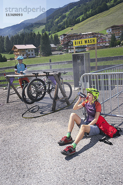 Mountainbiker entspannen sich nach einer Radtour und ihre Freundin putzt die Fahrräder  Zillertal  Tirol  Österreich