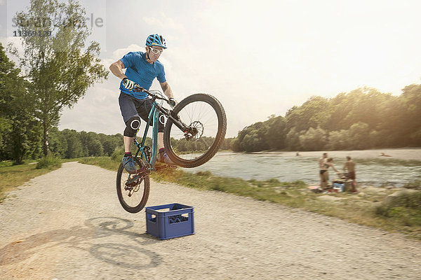 Mann springt mit Mountainbike über Bierkiste