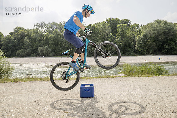 Mann springt mit Mountainbike über Bierkiste