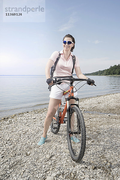 Ältere Frau mit Fahrrad am Seeufer
