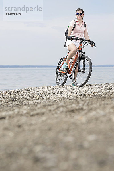 Ältere Frau mit Fahrrad am Seeufer