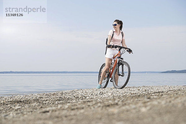 Ältere Frau mit Fahrrad am Seeufer