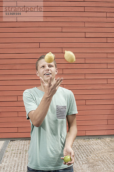 Junger Mann jongliert mit Zitronen