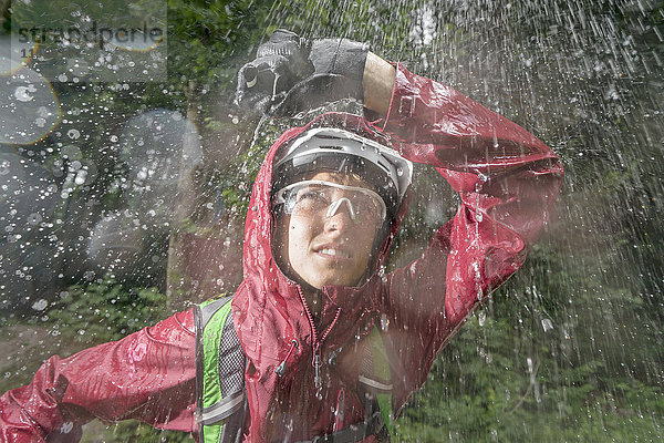 Mountainbiker im Regen stehend mit Hand über Kopf  Kampenwand