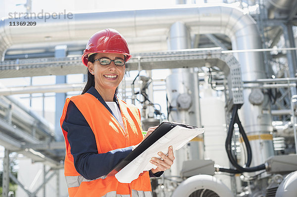 Porträt einer lächelnden Ingenieurin mit Dokument in einem geothermischen Kraftwerk