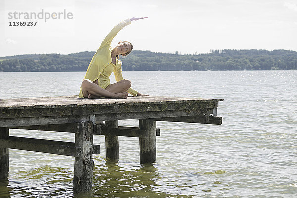 Frau beim Yoga auf der Uferpromenade am See  Ammersee  Oberbayern  Deutschland