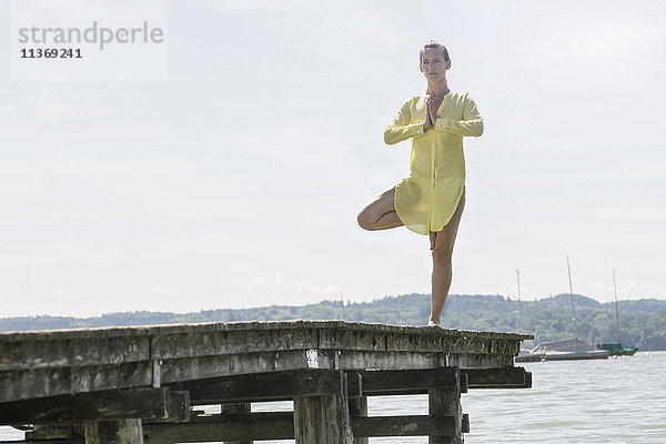 Frau beim Yoga in Baumhaltung auf dem Steg am See  Ammersee  Oberbayern  Deutschland