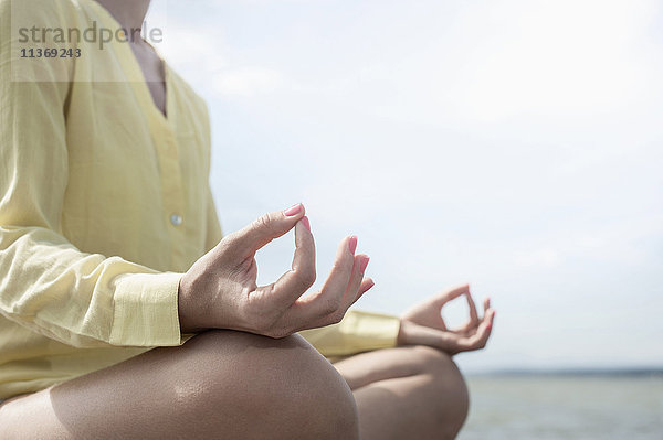 Mittelteil einer Frau beim Yoga im Lotussitz am See  Ammersee  Oberbayern  Deutschland