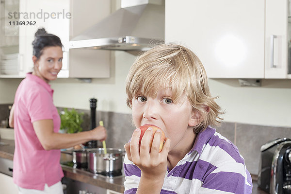 Junge isst einen Apfel in der Küche
