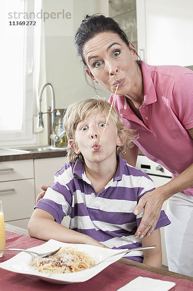 Porträt einer Frau mit ihrem Sohn  die auf lustige Weise Spaghetti essen
