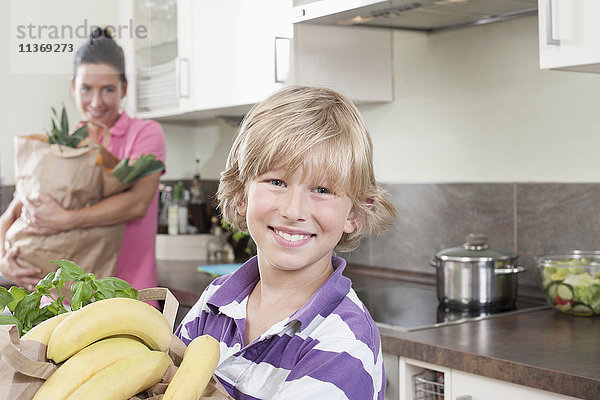 Junge mit seiner Mutter  die Tüten mit Lebensmitteln in der Küche hält