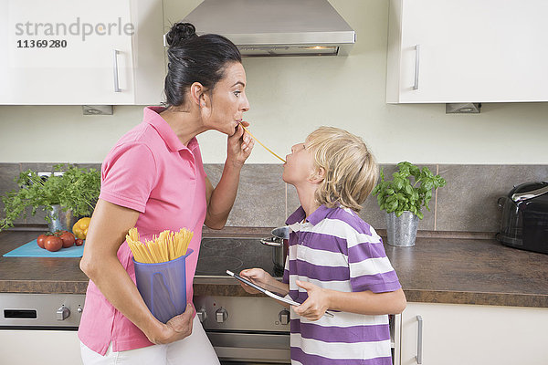 Frau mit ihrem Sohn spielt mit Spaghetti in der Küche