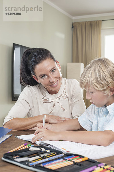 Frau hilft ihrem Sohn bei den Hausaufgaben