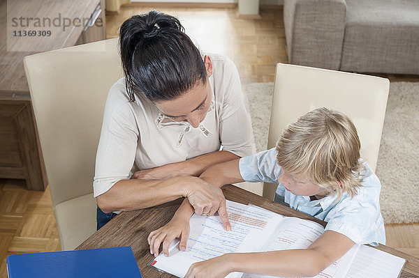 Frau hilft ihrem Sohn bei den Hausaufgaben