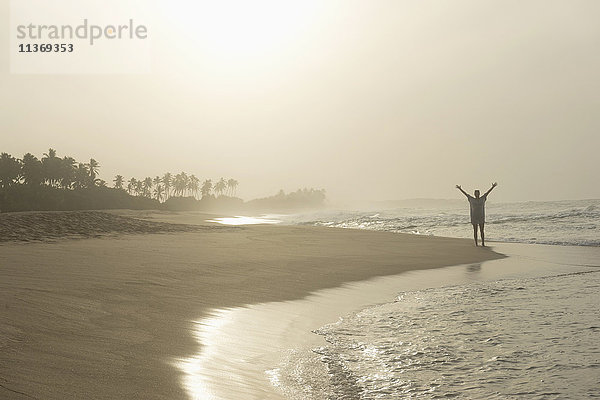 Frau steht mit ausgebreiteten Händen am Strand  Tangalle  Südprovinz  Sri Lanka