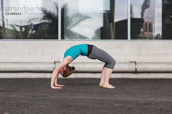 Junge Frau macht Brücke Pose auf der Straße in städtischen Stadt
