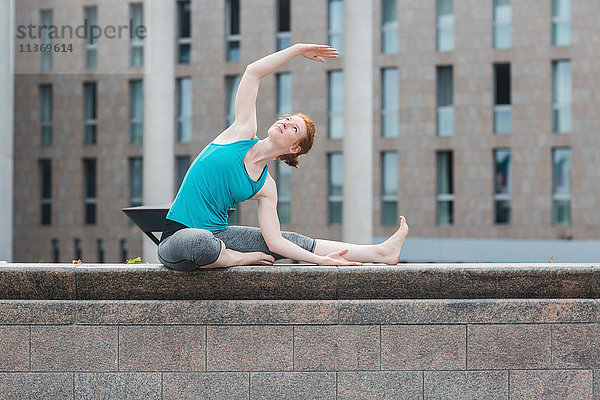 Junge Frau macht Yoga an einer Wand in einer Großstadt