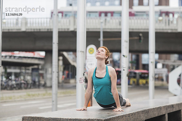 Junge Frau in Kobra-Pose in städtischer Stadt