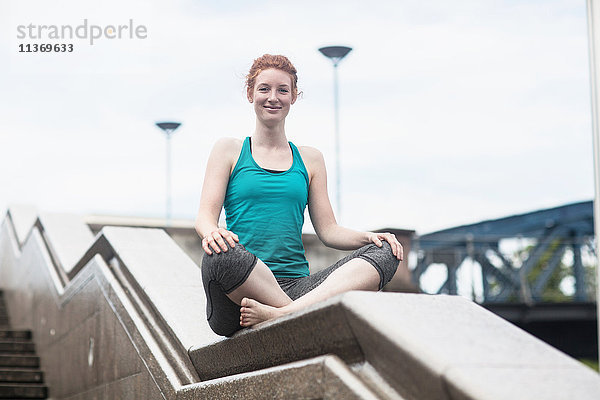 Junge Frau macht Yoga an einer Wand in einer Großstadt