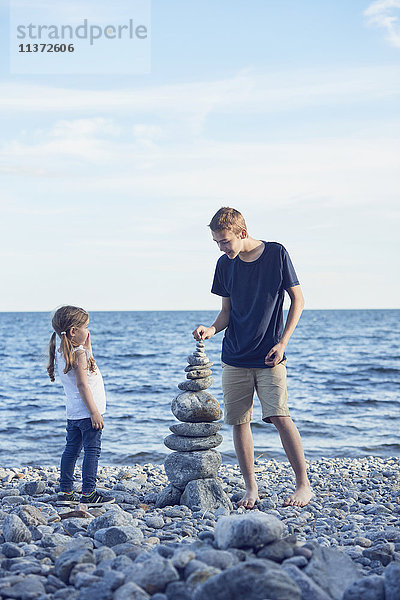 Bruder und Schwester stapeln Steine am Strand