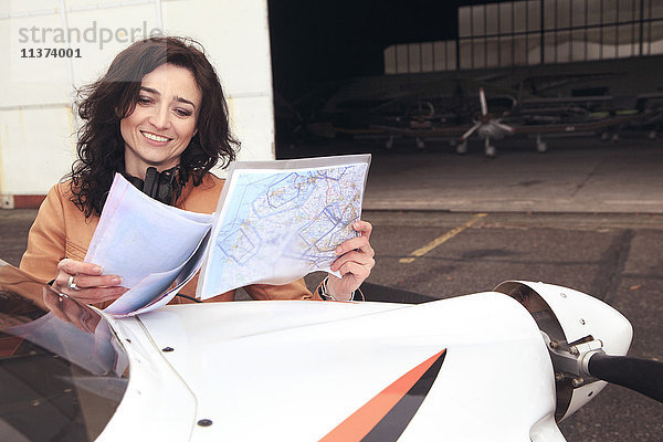 Pilotin auf einer Karte auf der Motorhaube ihres Ultraleichtflugzeuges.