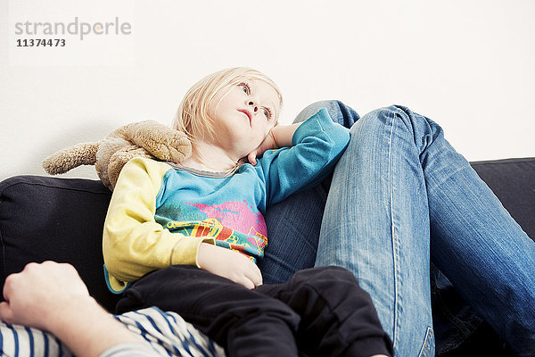 Mädchen entspannt mit Mutter auf Sofa