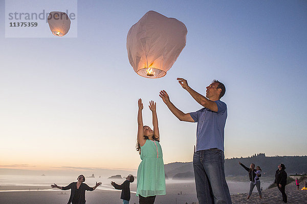 Kaukasischer Vater und Tochter fliegen Laterne Ballon am Strand