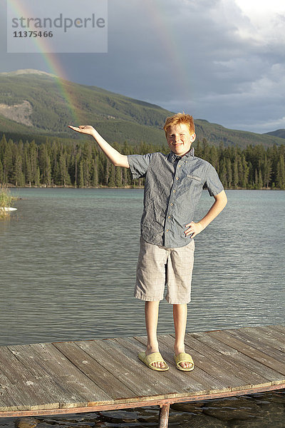 Kaukasischer Junge posiert auf dem Steg und fängt Regenbogen