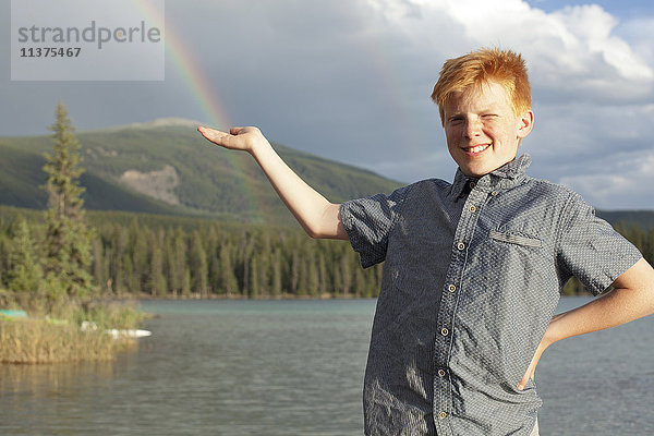 Kaukasischer Junge posiert am See und fängt Regenbogen