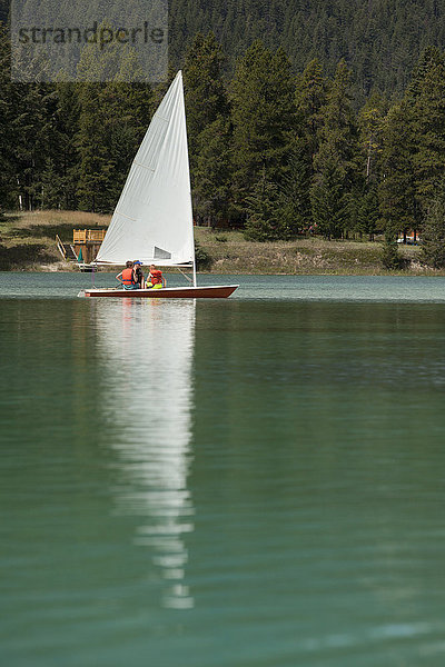 Kaukasische Jungen und Mädchen segeln auf einem See