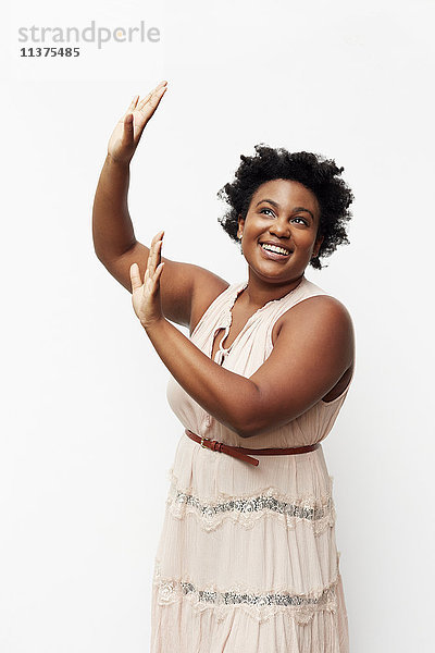 Porträt einer lächelnden schwarzen Frau mit erhobenen Armen