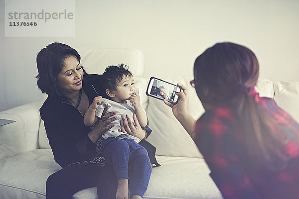 Indische Frau fotografiert Mutter und Sohn mit dem Handy