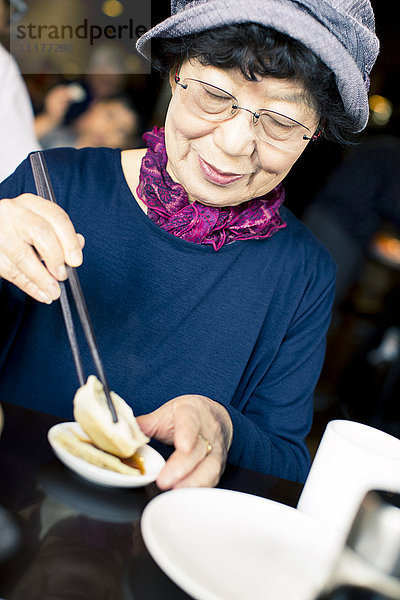 Ältere Japanerin beim Essen mit Stäbchen