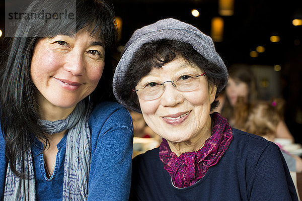 Ältere japanische Mutter und Tochter lächelnd im Restaurant