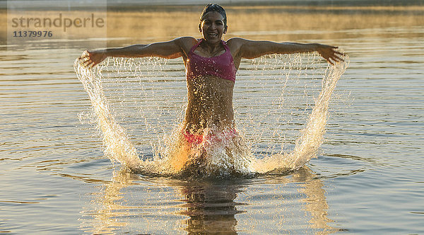 Gemischtrassige Frau plantscht im See