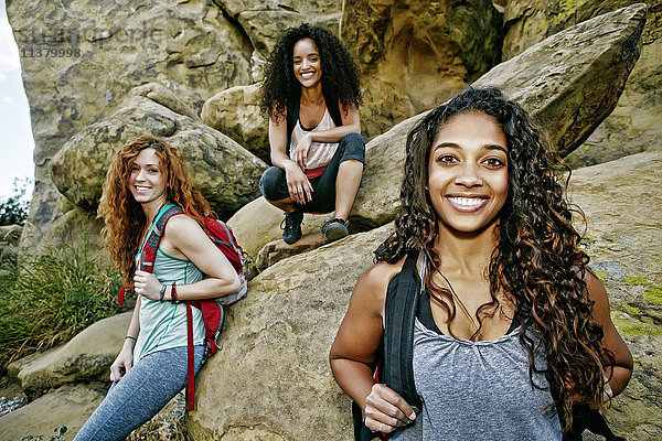 Lächelnde Frauen mit Rucksäcken in der Nähe einer Felsformation
