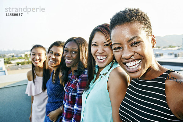 Lächelnde Frauen stehen in einer Reihe auf dem Dach