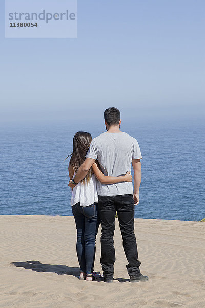 Hispanisches Paar bewundert Meereslandschaft am Strand