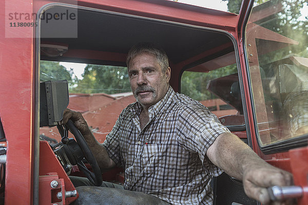 Kaukasischer Mann hält die Tür eines Traktors