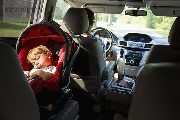 Kaukasische Mutter fährt Auto mit ihrem kleinen Sohn im Kindersitz