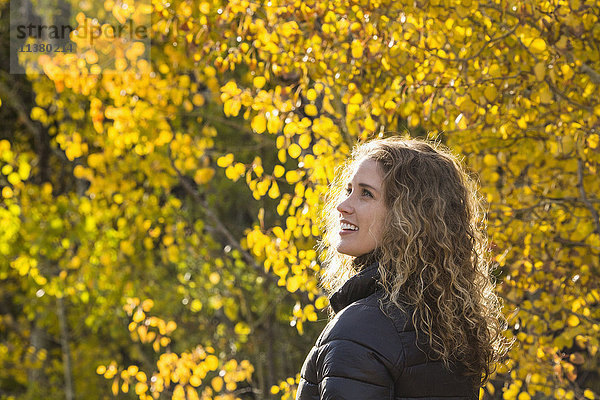 Lächelnde kaukasische Frau unter Herbstblättern