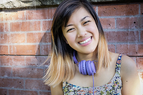 Porträt einer lächelnden chinesischen Frau mit Kopfhörern