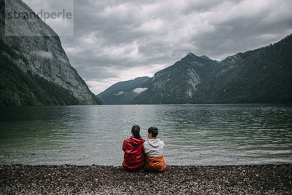 Kaukasisches Paar sitzt in der Nähe eines Bergsees