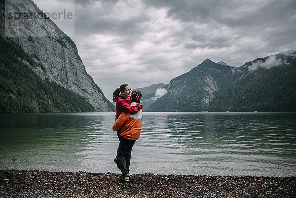 Kaukasischer Mann  der sich in der Nähe eines Bergsees umarmt