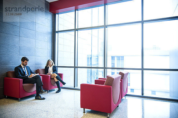 Geschäftsmann und Geschäftsfrau sitzen in einer Bürolounge