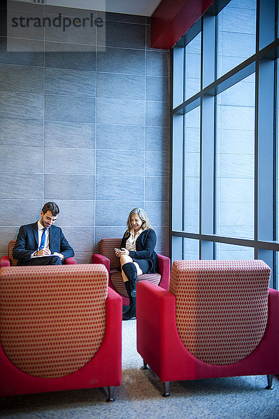 Geschäftsmann und Geschäftsfrau sitzen in einer Bürolounge