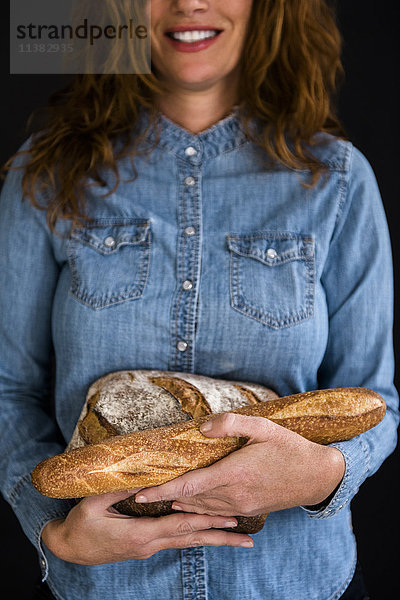 Lächelnde kaukasische Frau mit Brot in der Hand