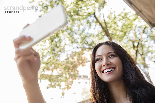 Lächelnde Thailänderin posiert für Handy-Selfie